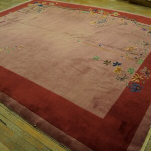 Mauve rug featuring a wide red border and scattered multicolor floral patterns on distressed wood flooring.