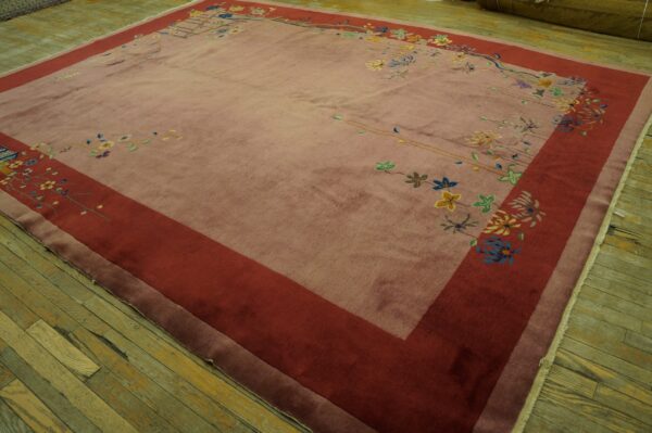 Mauve rug featuring a wide red border and scattered multicolor floral patterns on distressed wood flooring.