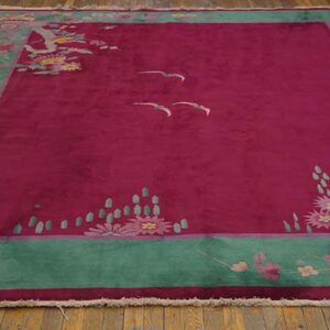 Deep pink rug featuring a teal border, stylized floral sprays, and two flying birds on wood flooring.