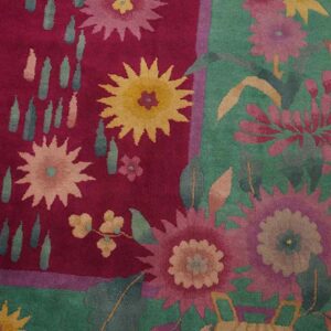 High-pile rug detail showing magenta and teal floral patterns next to hardwood flooring.
