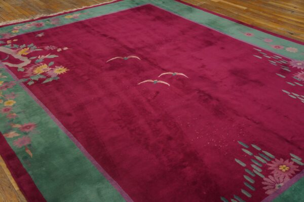 Plush magenta rug with high sheen, featuring green borders and stylized floral and bird patterns on wood.