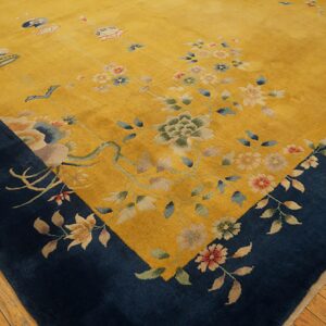Angled view of a yellow rug with a navy border and multicolor floral motifs on wood flooring.