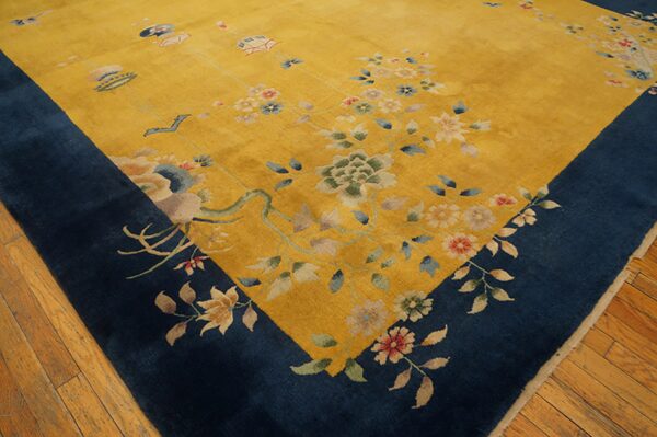 Angled view of a yellow rug with a navy border and multicolor floral motifs on wood flooring.