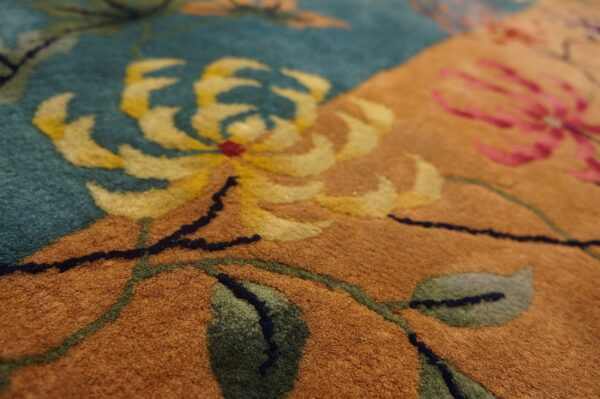Dense pile rug detail featuring yellow, pink, and green floral designs against teal and camel-colored sections.