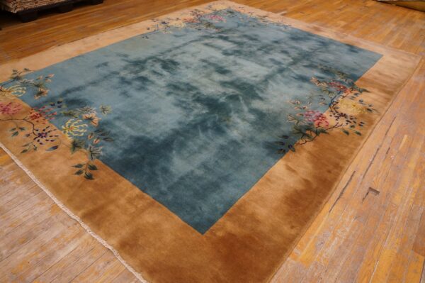 Plush teal rug with a golden tan border and corner floral patterns on distressed wood flooring.