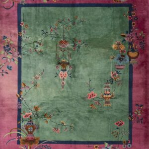 Green field rug with a magenta border featuring detailed florals, vases, and decorative lanterns.