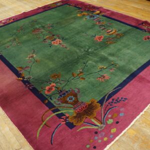 Vibrant green rug with detailed floral patterns and a wide contrasting magenta border on wooden floorboards.