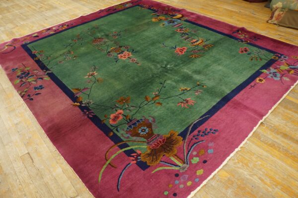 Vibrant green rug with detailed floral patterns and a wide contrasting magenta border on wooden floorboards.