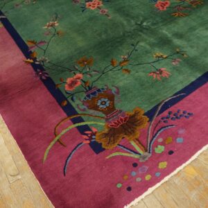 High-pile rug featuring a jade green field, magenta border, and multi-colored floral motifs on light wood flooring.