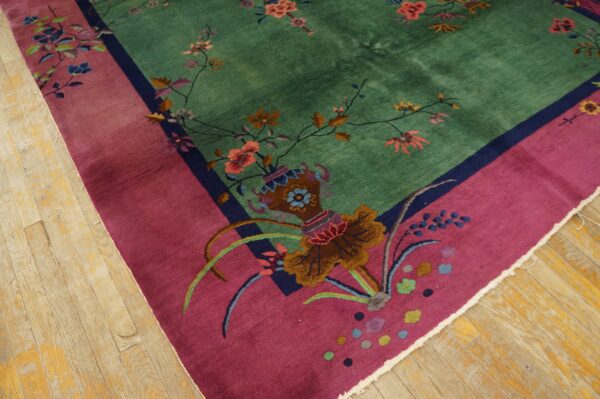 High-pile rug featuring a jade green field, magenta border, and multi-colored floral motifs on light wood flooring.