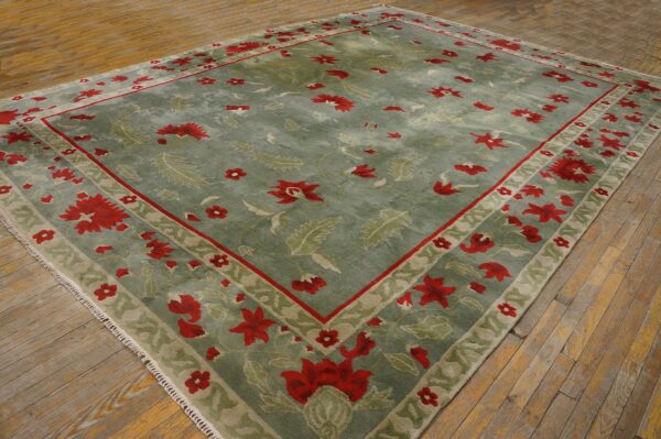 Green and red floral patterned rug resting on old, wide plank hardwood flooring.