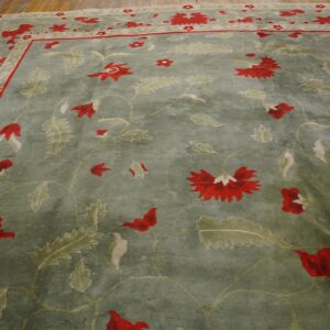 Green floral rug with bright red flowers and leafy motifs visible on hardwood planks.