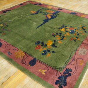 Green high-pile rug with a mauve border and multicolored floral and bird patterns on wood floors.