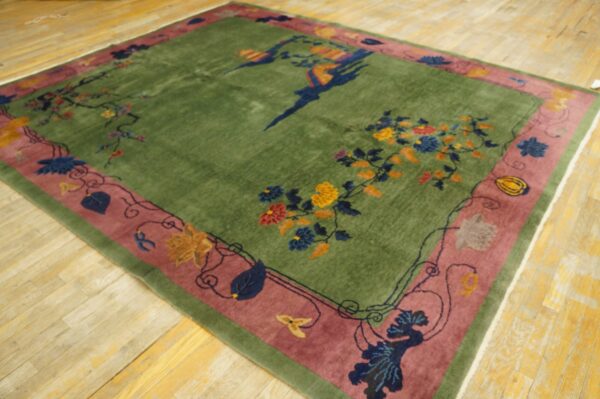Green high-pile rug with a mauve border and multicolored floral and bird patterns on wood floors.