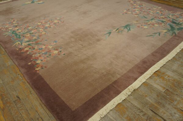 Mauve rug featuring a scattered floral and bamboo pattern with a dark border on distressed wood flooring.