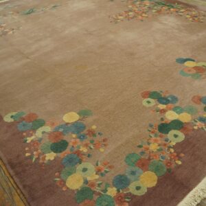 Taupe area rug with dense multicolored floral and circular patterns on a distressed wood floor.