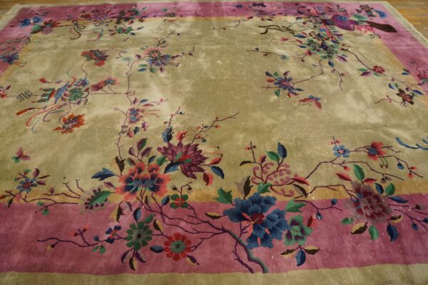 Greenish-gold rug with a rose border and vibrant blue, pink, and purple floral motifs on a wood floor.