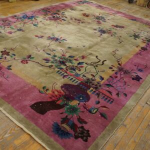 Floral area rug featuring an olive green field and wide magenta border on wooden plank flooring.