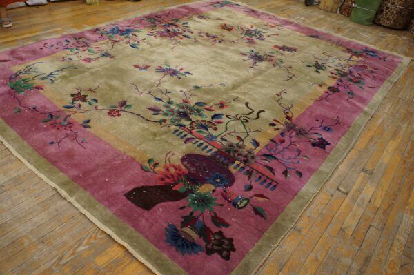 Floral area rug featuring an olive green field and wide magenta border on wooden plank flooring.