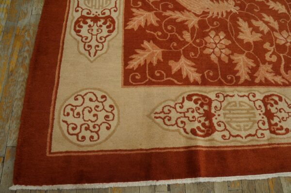 Rust and tan rug detail showing ornate scrollwork, botanical patterns, and a thick border on wooden planks.