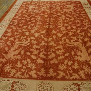 Terracotta rug features a dense botanical pattern, stylized birds, and ornate tan borders on worn wood planks.