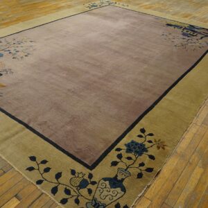 Mauve and khaki rectangular rug with a scenic border and dark outline rests on light hardwood flooring.