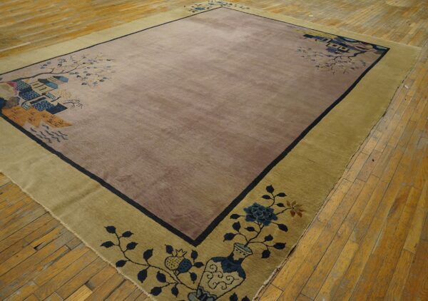 Mauve and khaki rectangular rug with a scenic border and dark outline rests on light hardwood flooring.