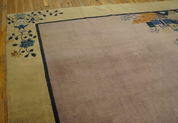 Low-pile rug with a mauve center and khaki border featuring blue and gold floral designs rests on wood floor.