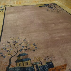 Muted taupe and gold bordered rug with scenic corner motifs of flowering trees and stylized buildings on hardwood floor.