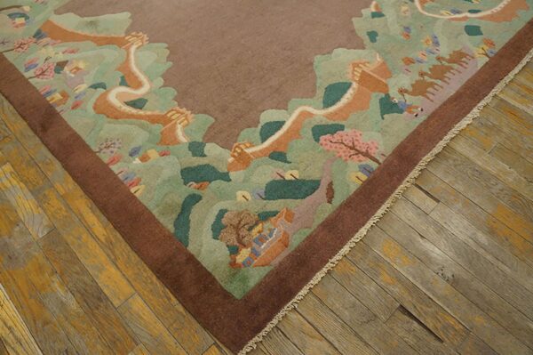 Brown bordered rug with a pastel scenic pattern of green hills, pink blossoms, and camels on distressed wood flooring.