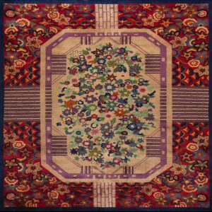 Tan central field with bright floral motifs surrounded by purple geometric lines and red floral borders.