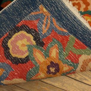 Multicolor floral rug folded over on wood flooring, revealing the bright high pile and woven backing.
