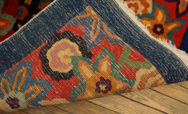 Multicolor floral rug folded over on wood flooring, revealing the bright high pile and woven backing.