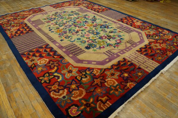 Multi-colored floral rug featuring a beige center field and bold red and geometric purple borders on wood flooring.