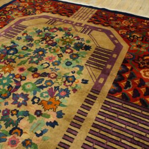 A vibrant rug with a tan floral center and red outer border featuring purple geometric accents on wood flooring.