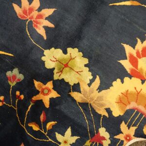 Dark blue plush rug with yellow, orange, and red floral patterns; the toe of a sneaker is visible.