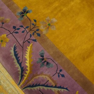 A high-pile rug displays a golden yellow field and a purple floral border next to distressed wood floors.