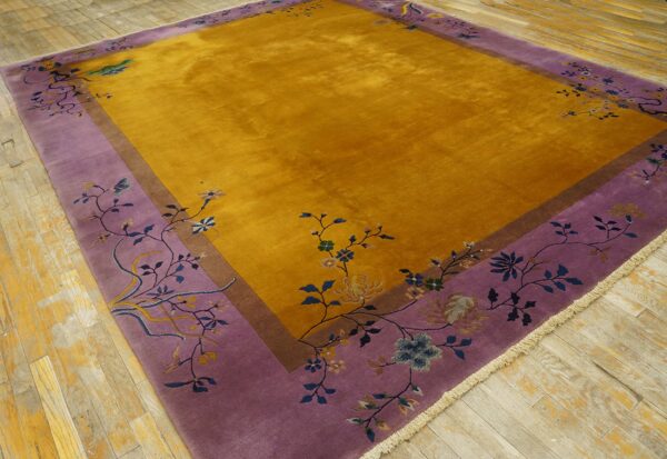 Golden yellow rug with a wide lavender floral border rests on distressed wood plank flooring.
