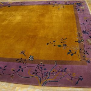 Shimmering ochre rug with a wide purple border featuring delicate blue and yellow floral vines over wood planks.