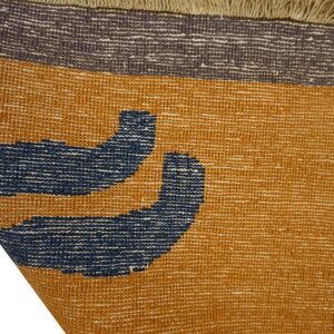 Textured flatweave rug detail in mustard yellow, navy blue, and charcoal gray with tan fringe.