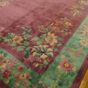 High-pile magenta rug with jade border features detailed botanical and scenic patterns on wood planks.