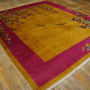 Golden yellow rug with a bright pink border and colorful flowering branches displayed on distressed hardwood.