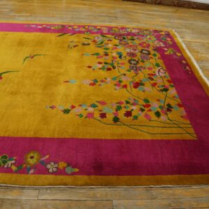 Plush yellow rug with bright pink borders and multi-colored flowers and flying birds rests on wood flooring.