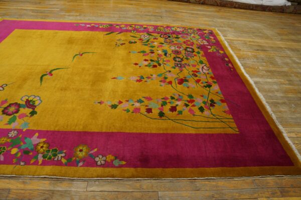 Plush yellow rug with bright pink borders and multi-colored flowers and flying birds rests on wood flooring.
