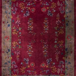 A deep red floral rug featuring multicolored blossoms and a wide taupe border with connecting vines.