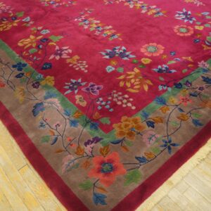 Close-up of a magenta floral rug featuring a colorful vine border on light, distressed wooden planks.