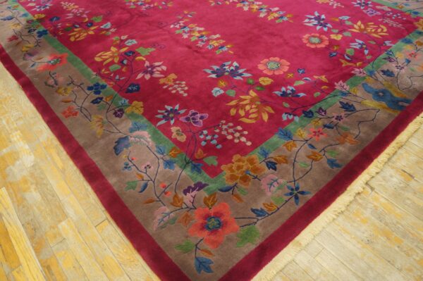 Close-up of a magenta floral rug featuring a colorful vine border on light, distressed wooden planks.