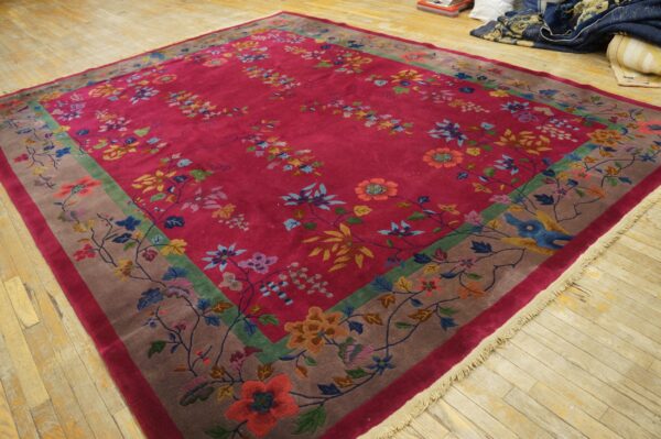 High-pile magenta rug with scattered multicolor florals and a decorative wide taupe and green border on wood planks.