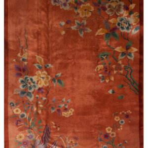 Terracotta rug with a visible sheen and wide border, displaying stylized multi-color floral branches.