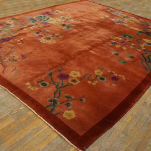 Lustrous rust rug with yellow and green floral branches displayed on worn plank hardwood floors.